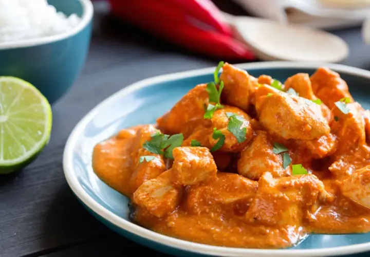 Bocconcini di pollo in salsa cremosa, guarniti con prezzemolo fresco, accompagnati da riso bianco e spicchio di lime.