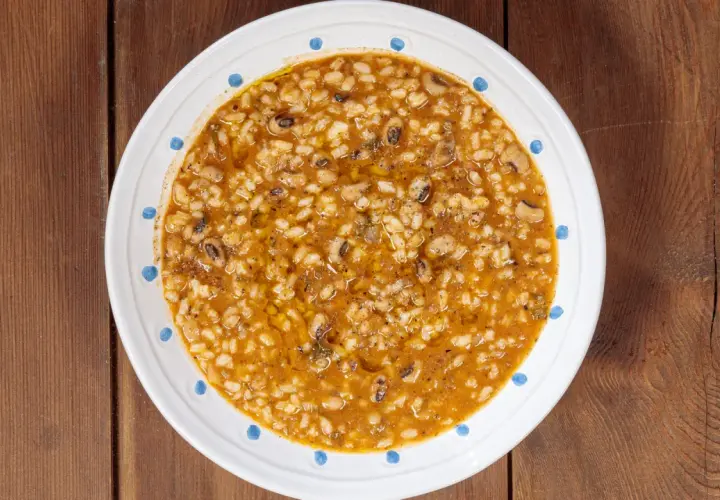 Piatto di riso e fagioli, un classico confortante, servito in una ciotola bianca con decorazioni blu su un tavolo di legno.