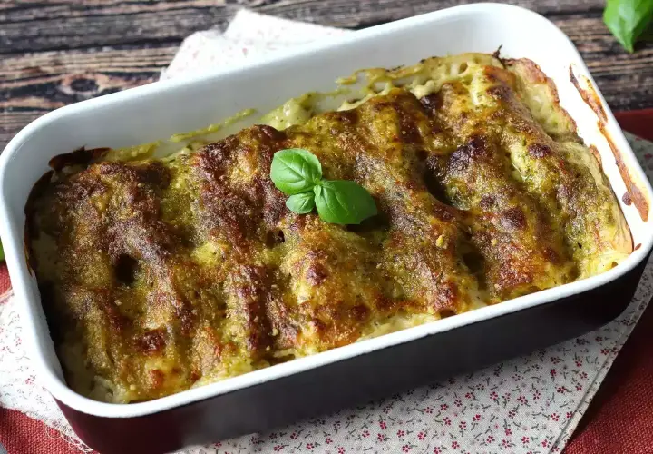 Cannelloni ricotta e spinaci appena sfornati, dorati e profumati, guarniti con una fogliolina di basilico fresco.