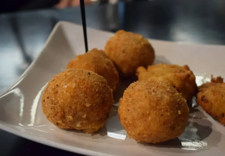Deliziosi arancini di riso dorati e croccanti, serviti su un piatto bianco.