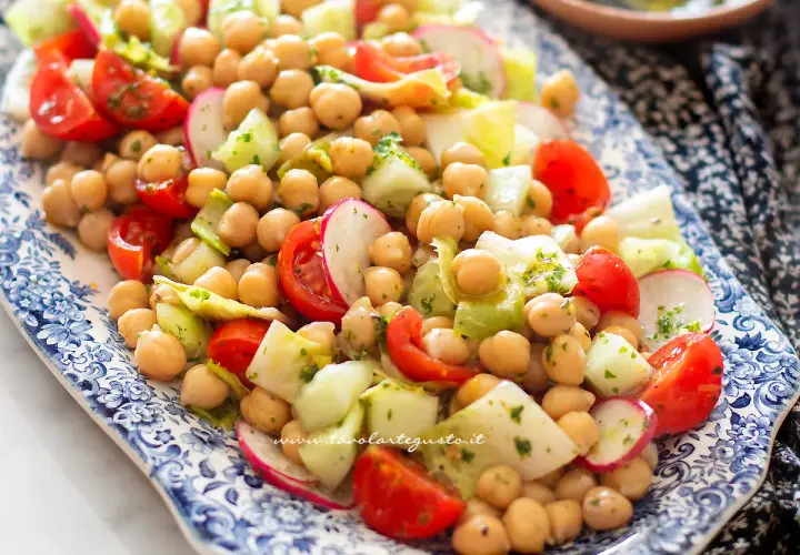 Un'insalata di ceci fresca e colorata con pomodorini, cetrioli e ravanelli, condita con erbe aromatiche.