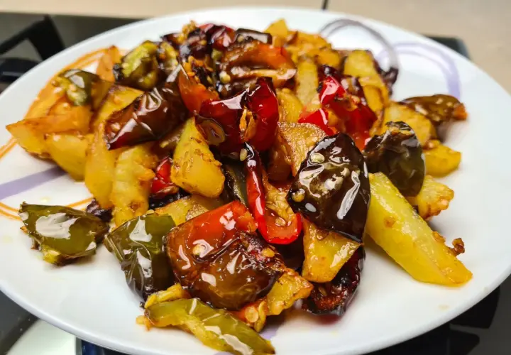 Un piatto invitante di **pipi e patate** saltate, con peperoni verdi e rossi croccanti e patate dorate, condite con spezie.