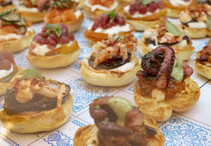 Varietà di antipasti di pesce su pane tostato: polpo grigliato, gamberi, tonno e salmone. Un'esplosione di sapori marini.