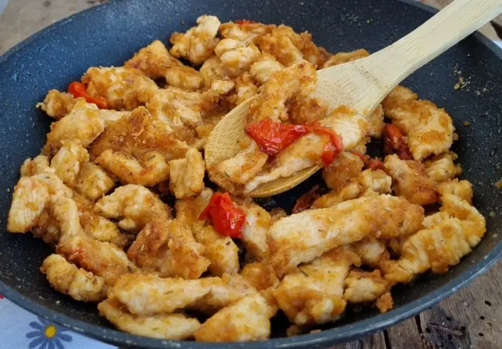 Straccetti di pollo saporiti cotti in padella con pomodorini e erbe aromatiche, pronti per essere gustati.