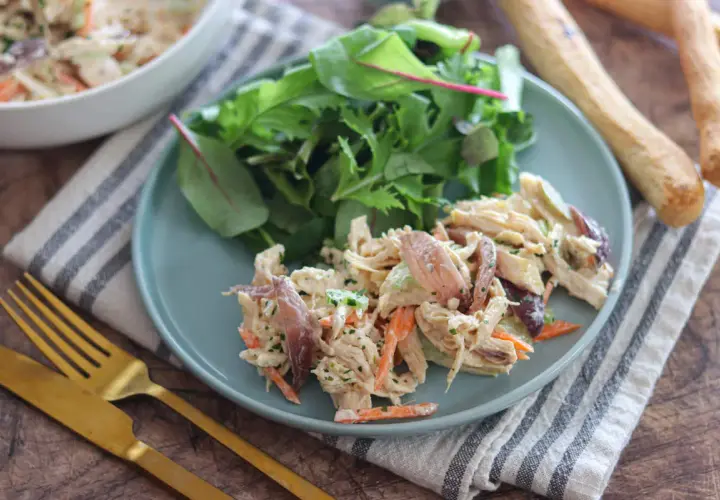 Deliziosa insalata di pollo con carote, sedano e un tocco di erbe fresche, servita con un contorno di insalata mista.