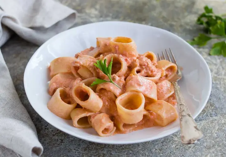 Un piatto invitante di pasta al tonno con una cremosa salsa rosa, guarnito con prezzemolo fresco.