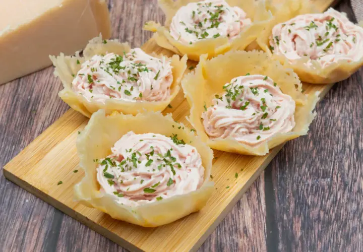 Deliziosi cestini di parmigiano ripieni di crema rosa e guarniti con erba cipollina. Un antipasto elegante e gustoso.