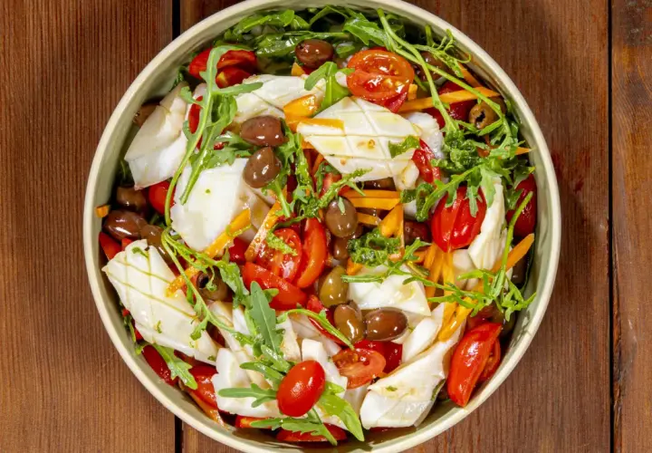Insalata di calamari fresca con pomodorini, olive, rucola e carote julienne, un piatto estivo colorato e saporito.