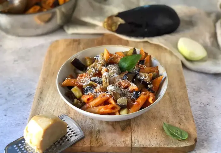 Piatto di pasta alla norma, un classico della ricetta della nonna, con melanzane, pomodoro e ricotta salata grattugiata.