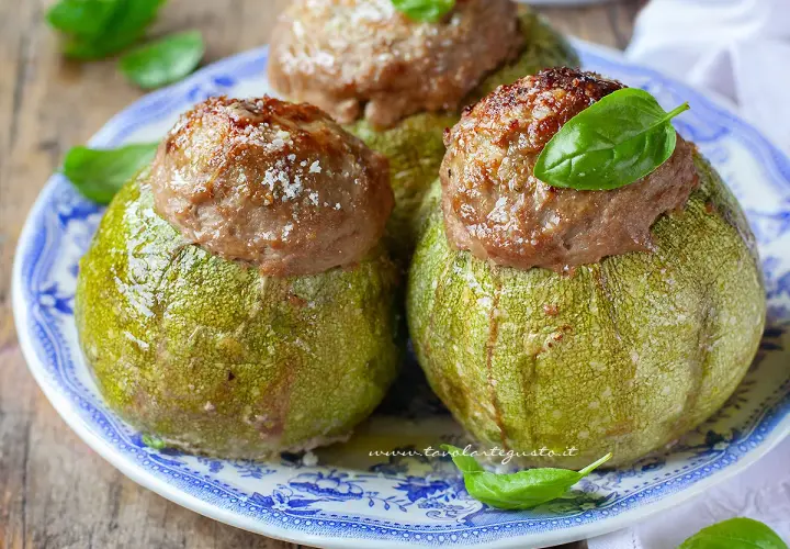 Zucchine tonde ripiene, un piatto gustoso e colorato, guarnito con basilico fresco e parmigiano.