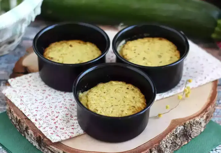 Tre deliziosi flan di zucchine appena sfornati in stampini neri, pronti per essere gustati.