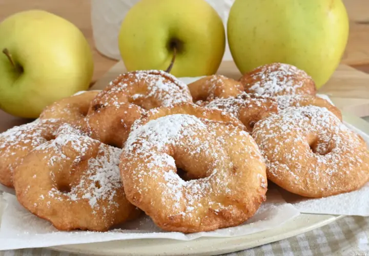 Frittelle di mele dorate e spolverate di zucchero a velo, pronte per essere gustate.