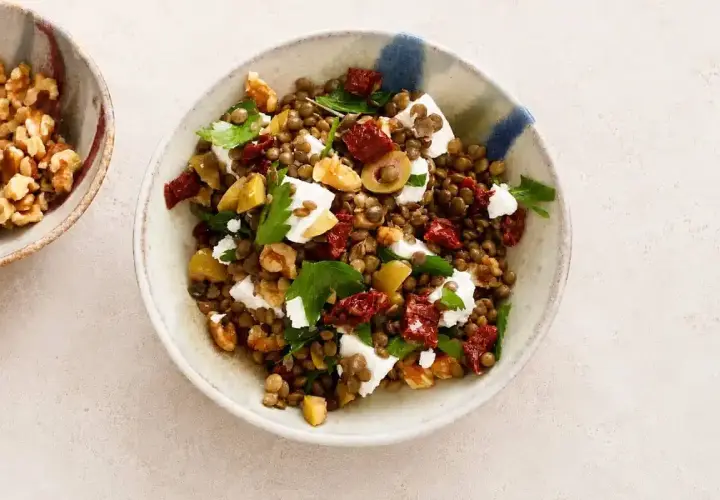 Insalata di lenticchie estiva con feta, pomodori secchi, olive e noci. Fresca e saporita, perfetta per un pasto leggero.