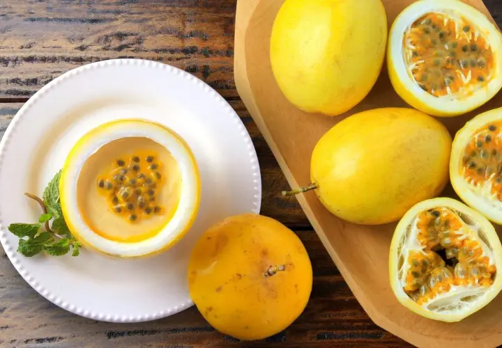 Deliziosa mousse al limone servita in un frutto della passione, guarnita con menta. Frutti della passione freschi completano la scena.