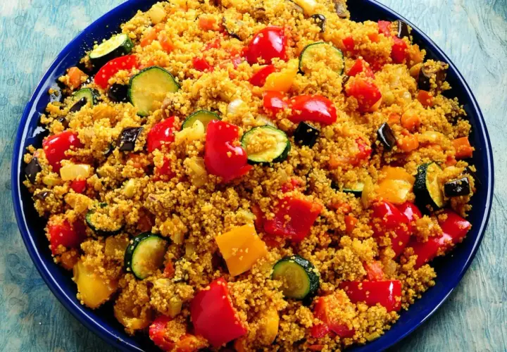 Un piatto colorato di cous cous con verdure miste: peperoni rossi e gialli, zucchine e melanzane. Una deliziosa ricetta cous cous.