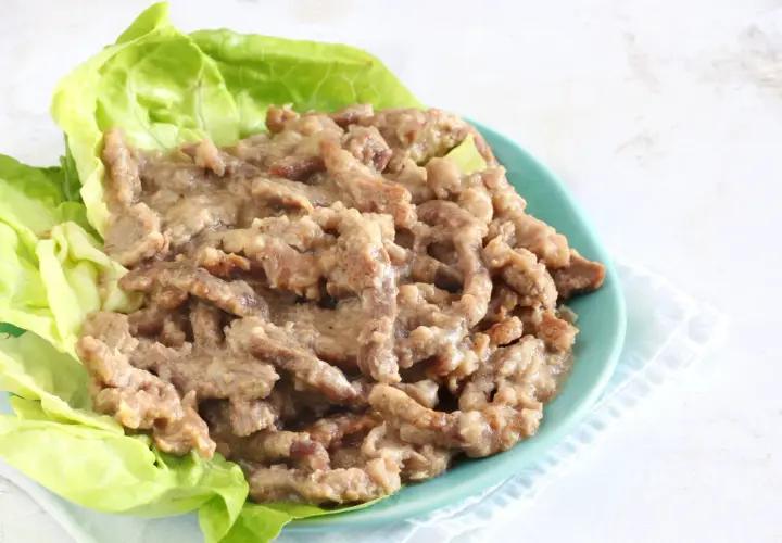 Straccetti di manzo succulenti serviti su foglie di lattuga fresca, un piatto invitante e saporito.