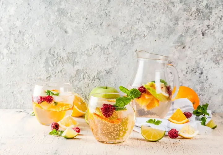Sangria bianca ricetta: bicchieri e caraffa pieni di frutta fresca, ghiaccio e menta. Perfetta per l'estate!