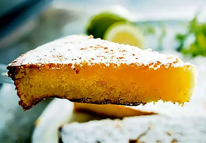 Una fetta di caprese al limone, soffice e profumata, cosparsa di zucchero a velo.