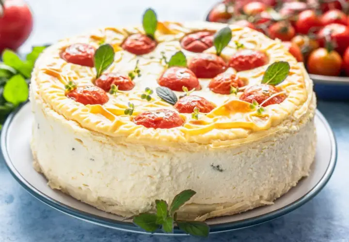 Cheesecake salata con taralli, decorata con pomodorini confit e basilico. Un'idea sfiziosa per un aperitivo o antipasto.