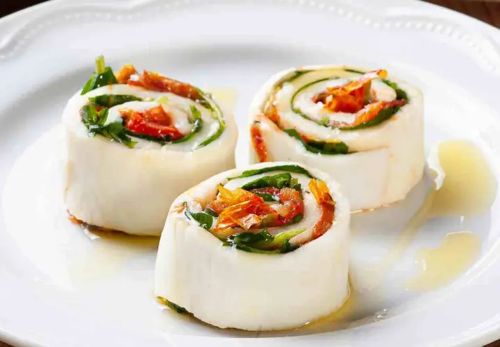 Rotolini di sfoglia di mozzarella come riempirla con pomodori secchi e basilico, conditi con olio.