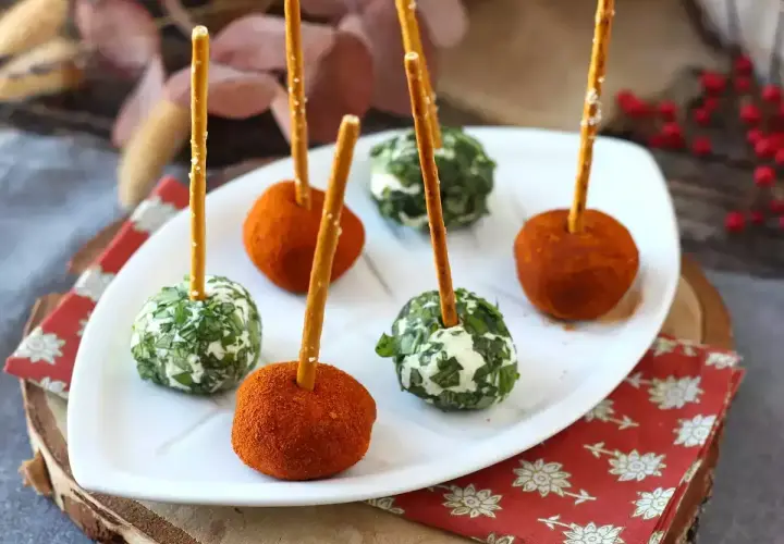 Sfere di ricotta al forno, alcune ricoperte di erbe fresche, altre di paprika, infilzate con grissini.