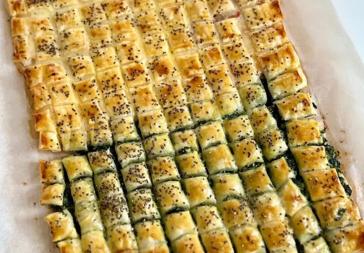 Pasticcio di pasta sfoglia rettangolare con ripieno verde, tagliato a quadretti e cosparso di semi. Un'idea su come farcire pasta sfoglia rettangolare.