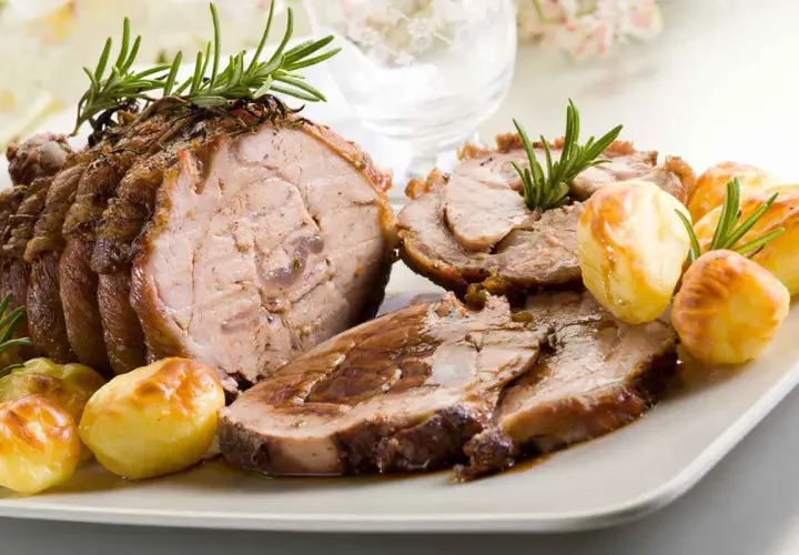 Succulento arrosto di vitello, affettato e servito con patate arrosto e rametti di rosmarino.