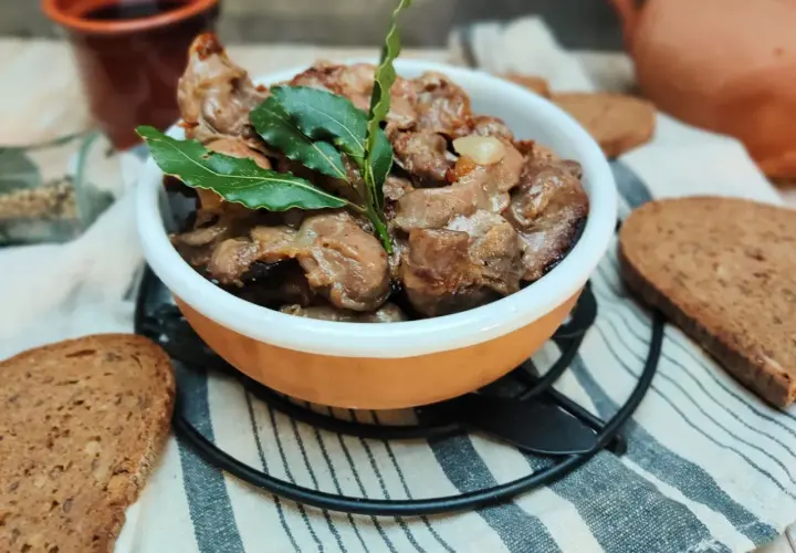 Durelli di pollo saporiti in ciotola, guarniti con foglie di alloro, accompagnati da fette di pane rustico.