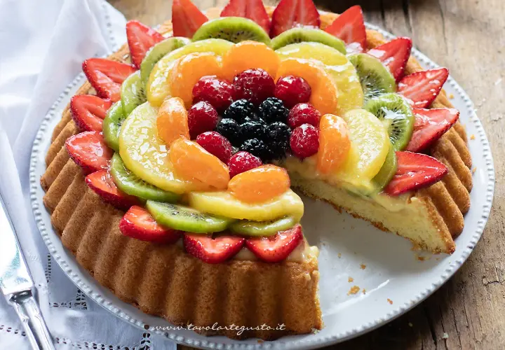 Una deliziosa crostata di frutta, con fragole, kiwi, mandarini, lamponi e mirtilli su una base di crema pasticcera.