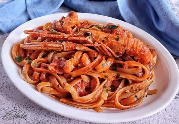 Un piatto invitante di linguine agli scampi, condite con un sugo rosso e guarnite con prezzemolo fresco.
