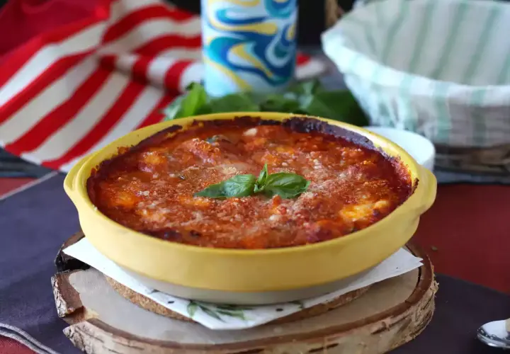Gnocchi alla sorrentina appena sfornati, dorati e filanti, con basilico fresco. Un piatto invitante e saporito.