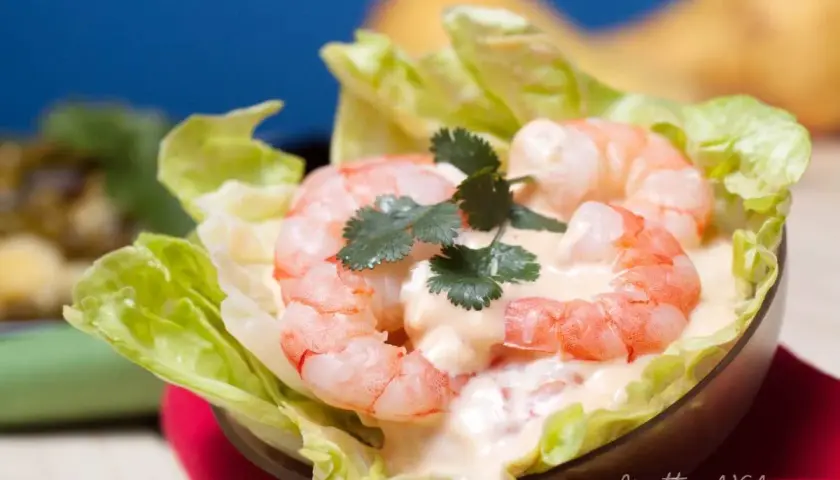 Gamberetti succulenti in salsa rosa cremosa, serviti su foglie di lattuga croccante. Un antipasto fresco e invitante.