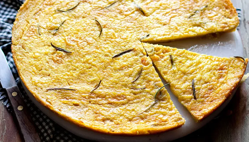 Farinata di ceci dorata e profumata al rosmarino, appena sfornata e tagliata a spicchi, pronta per essere gustata.