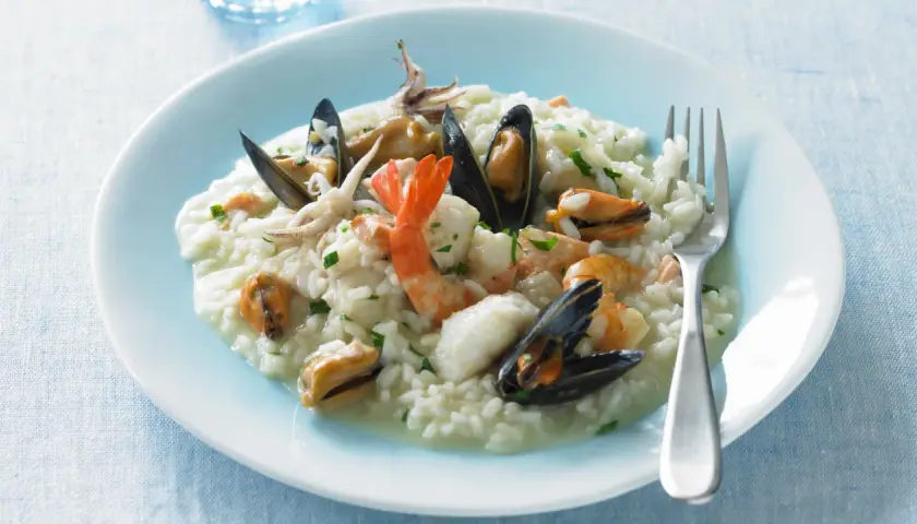 Un cremoso risotto alla pescatora, ricco di cozze, gamberi e calamari, pronto per essere gustato.