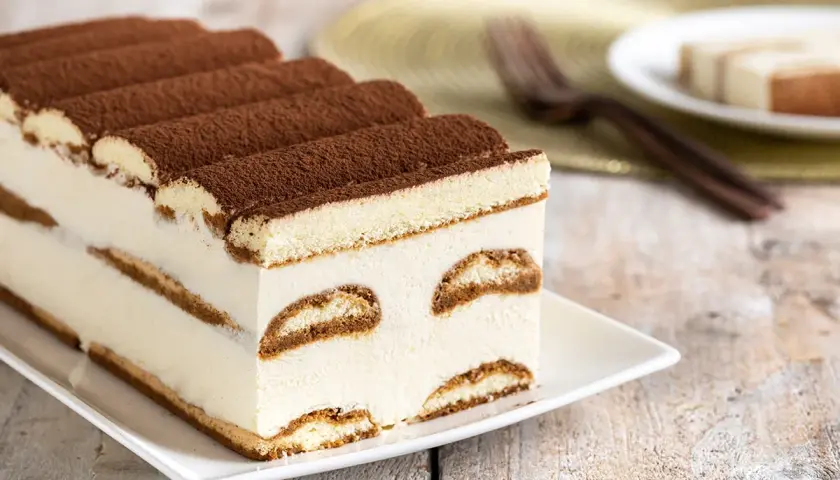 Tiramisù cremoso e soffice, un dolce senza glutine perfetto per ogni occasione. Strati di savoiardi senza glutine e crema al mascarpone, spolverato di cacao.