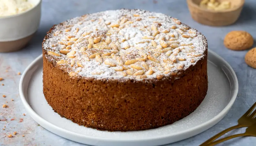 Torta rustica con farina di mandorle, guarnita con pinoli e zucchero a velo. Perfetta per ogni occasione.