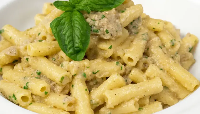 Un piatto invitante di pasta con melanzane in bianco cremosa, guarnito con basilico fresco.