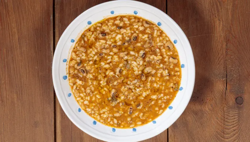 Piatto di riso e fagioli, un classico confortante, servito in una ciotola bianca con decorazioni blu su un tavolo di legno.