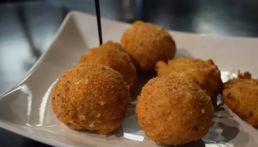 Deliziosi arancini di riso dorati e croccanti, serviti su un piatto bianco.