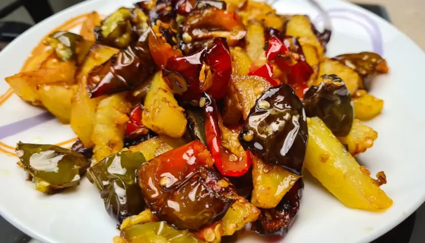 Un piatto invitante di **pipi e patate** saltate, con peperoni verdi e rossi croccanti e patate dorate, condite con spezie.