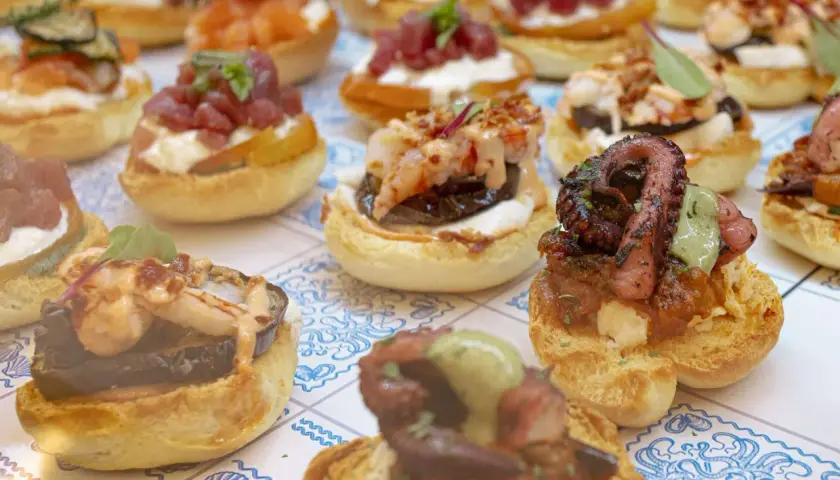 Varietà di antipasti di pesce su pane tostato: polpo grigliato, gamberi, tonno e salmone. Un'esplosione di sapori marini.