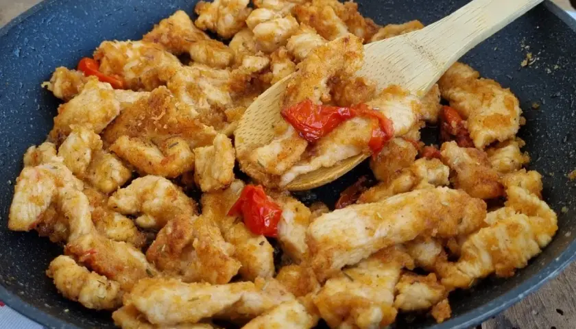 Straccetti di pollo saporiti cotti in padella con pomodorini e erbe aromatiche, pronti per essere gustati.