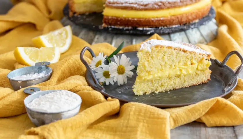 Una fetta di torta paradiso, soffice e farcita di crema, pronta per essere gustata. La ricetta perfetta per un dolce fatto in casa.