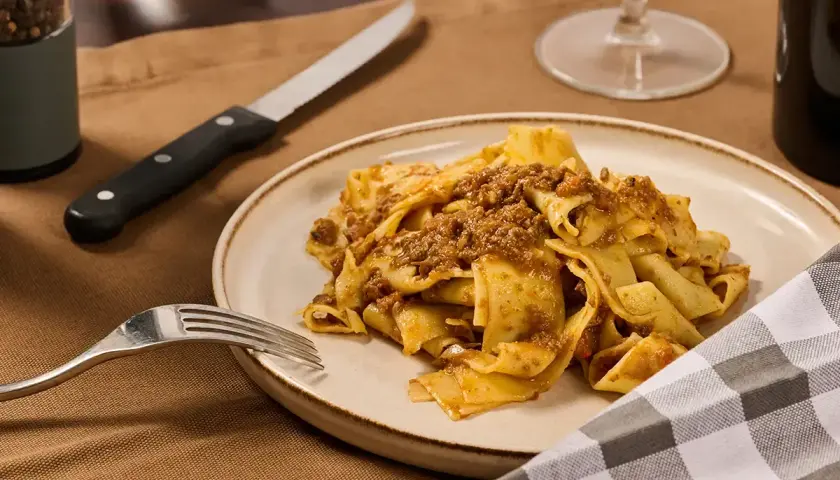 Piatto di pappardelle al cinghiale, un classico della cucina toscana, pronto per essere gustato.