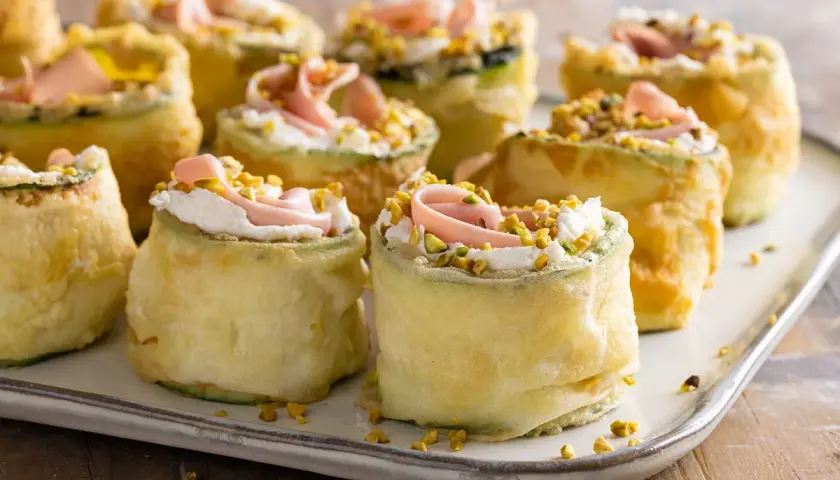 Rotolini di zucchine fritte con crema, prosciutto e pistacchi: stuzzichini veloci ed economici per aperitivo.