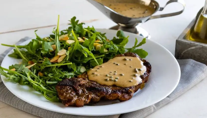 Un succulento filetto al pepe verde, nappato con la sua salsa cremosa, accompagnato da un'insalata fresca di rucola e mandorle.