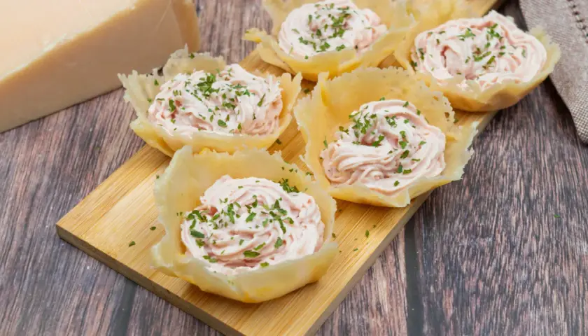 Deliziosi cestini di parmigiano ripieni di crema rosa e guarniti con erba cipollina. Un antipasto elegante e gustoso.