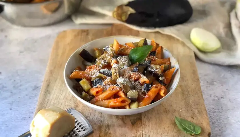 Piatto di pasta alla norma, un classico della ricetta della nonna, con melanzane, pomodoro e ricotta salata grattugiata.