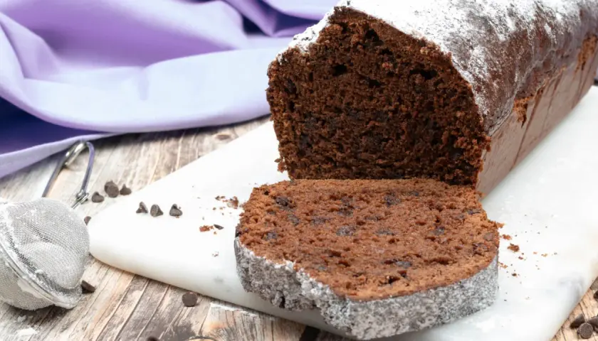 Un soffice plumcake al cioccolato, cosparso di zucchero a velo, pronto per essere gustato.