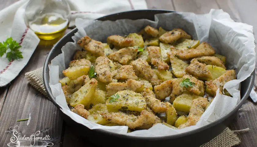 Straccetti di pollo al forno con patate, dorati e croccanti, guarniti con prezzemolo fresco.